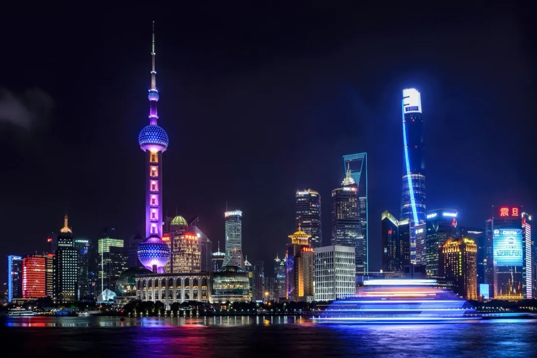 A night skyline of a major Asian city lit up beside its river, illustrating the coronavirus's impact on the economy