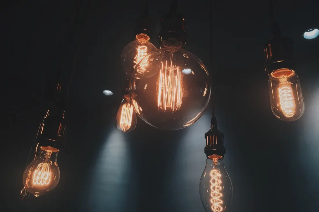 Row of glowing filament lightbulbs hanging in a dark room, illustrating digital energy management