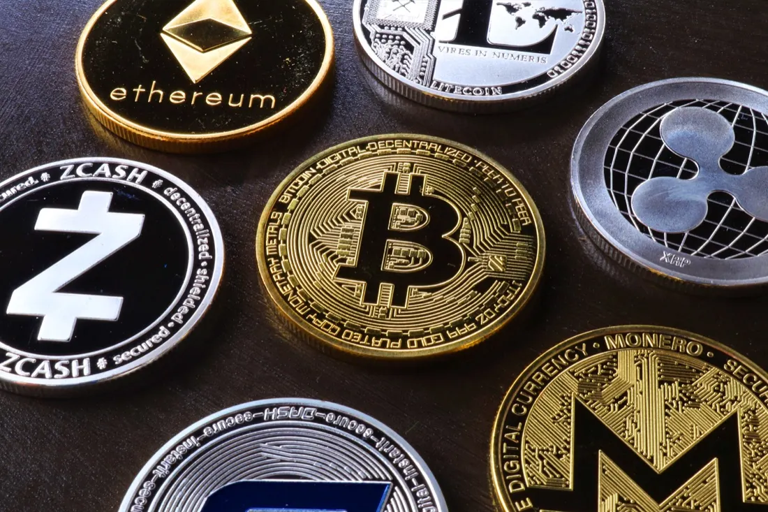 Assorted cryptocurrency coins including Bitcoin and Ethereum arranged on a dark surface, illustrating borrowing to fund crypto