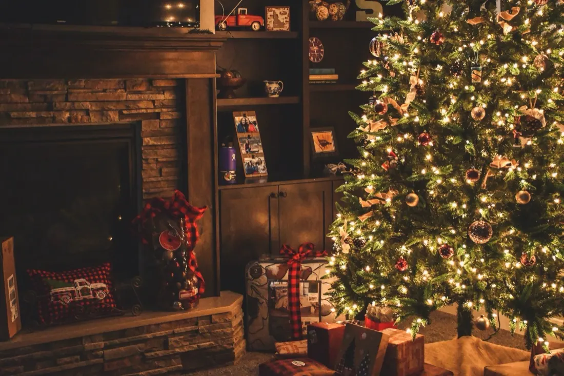 A decorated Christmas tree beside a lit fireplace, illustrating unapproved staff absence over the festive period