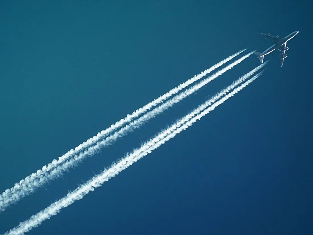 A jet aircraft leaving twin vapour trails across a blue sky, illustrating global consumer confidence hitting a record high