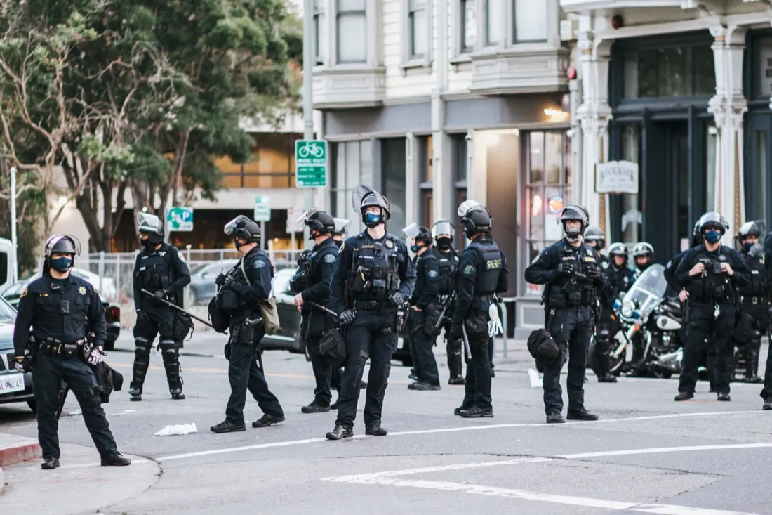 Police officers in riot gear standing in a city street, illustrating threats of violence to companies