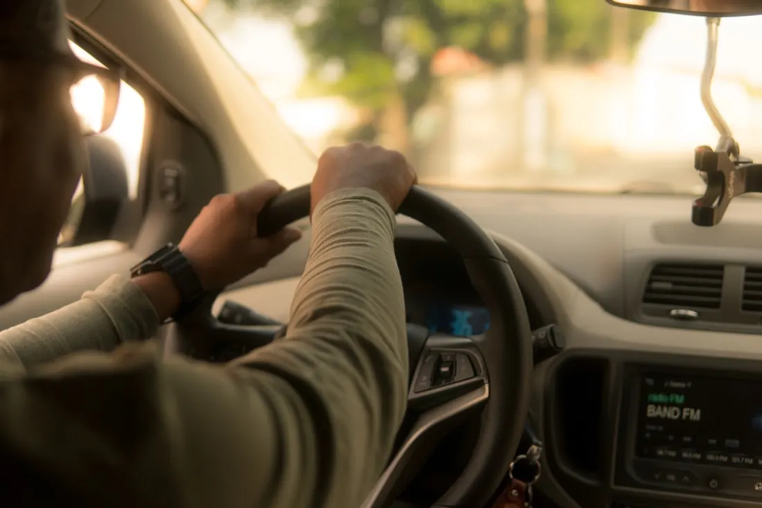 A driver's hands gripping the steering wheel inside a car, illustrating worker classification in the gig economy