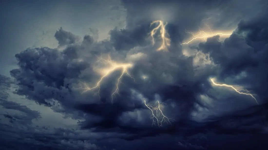 Dark storm clouds lit by multiple lightning strikes, illustrating a weaker economic outlook and funding costs