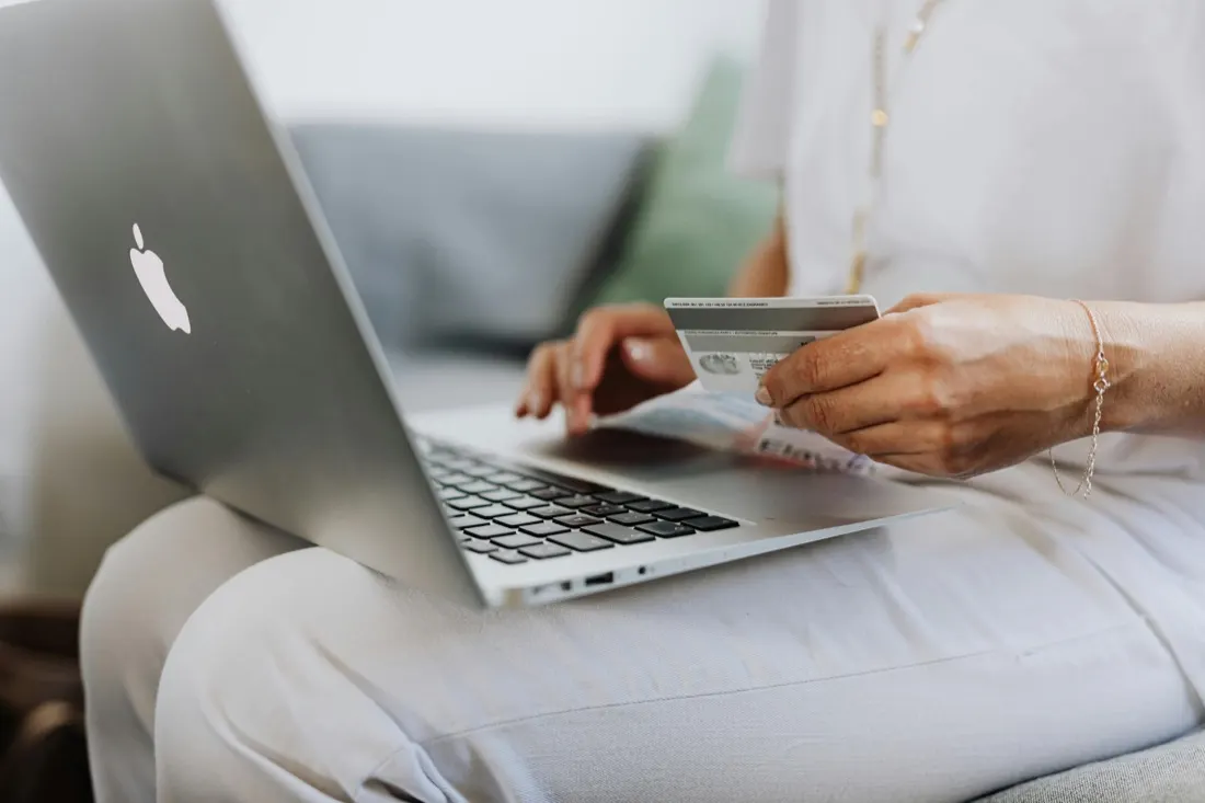 Person typing on a laptop while holding a payment card, illustrating trust in online shopping