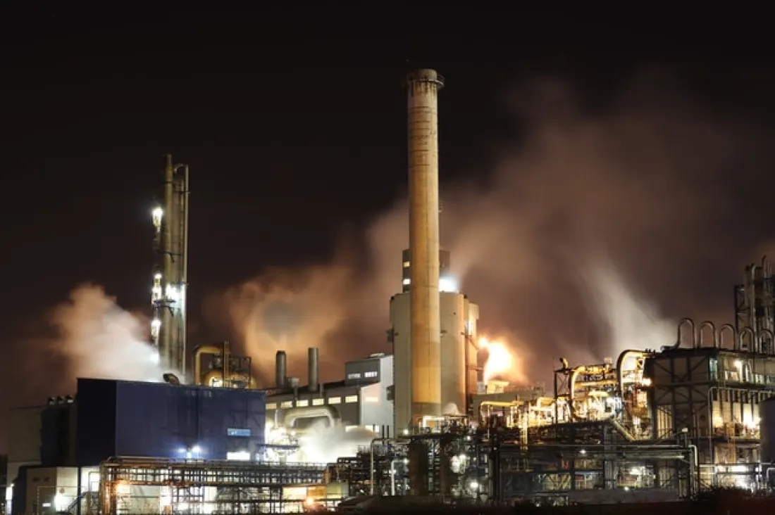 An industrial plant lit up at night with steam and smoke rising from its chimneys, set against the CSR debate in the Middle East and North Africa