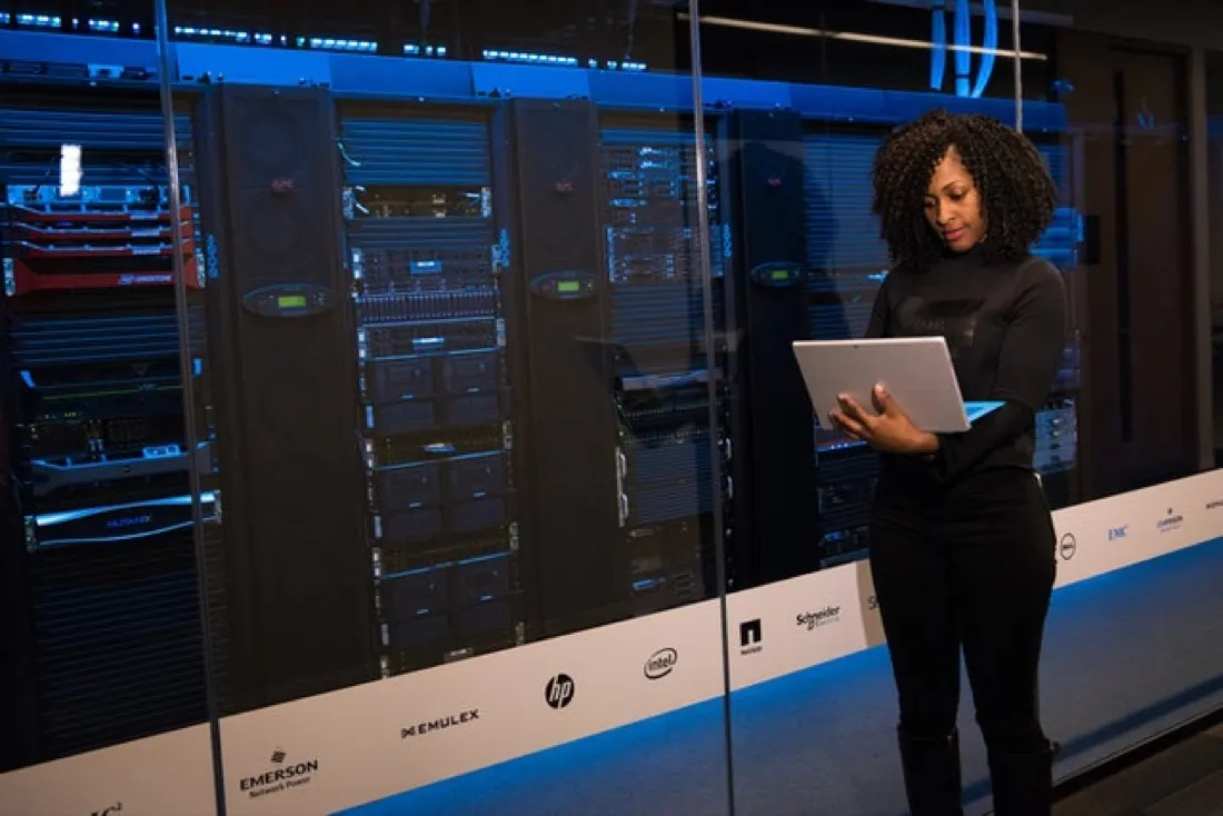 A businesswoman checking a laptop in front of server racks in a data centre, reflecting the push for IT agility