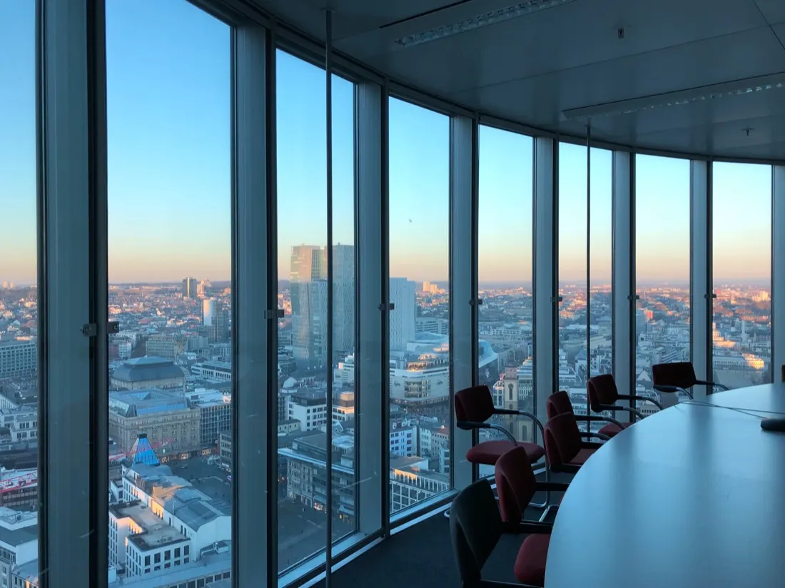 Empty boardroom with red chairs overlooking a city skyline at dusk, illustrating C-suite well-being concerns
