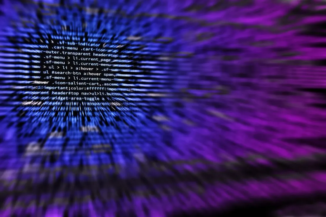 A blurred close-up of purple and blue computer code on a screen, illustrating cyber criminals targeting MSPs