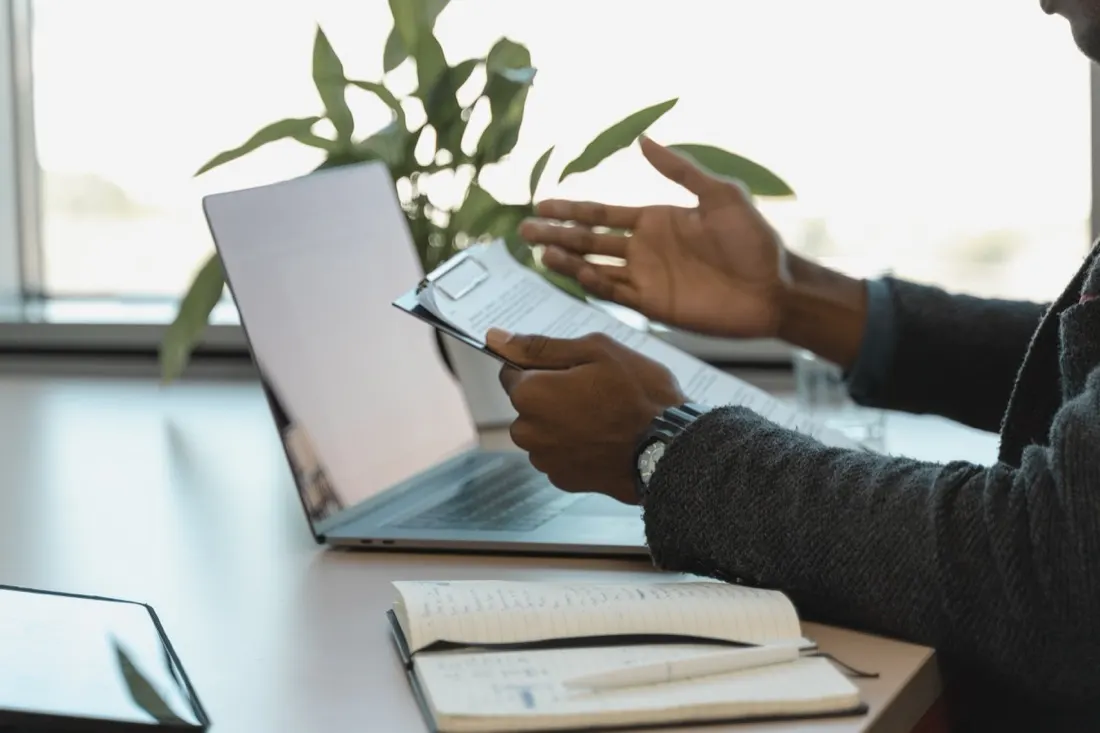 A businessman reviewing a document beside an open laptop, illustrating employers turning to silver medallists