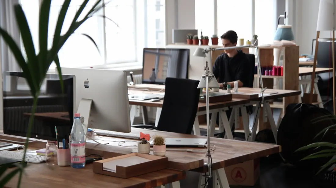 Open-plan office with standing desks and a worker at a computer, illustrating contingent workforce management