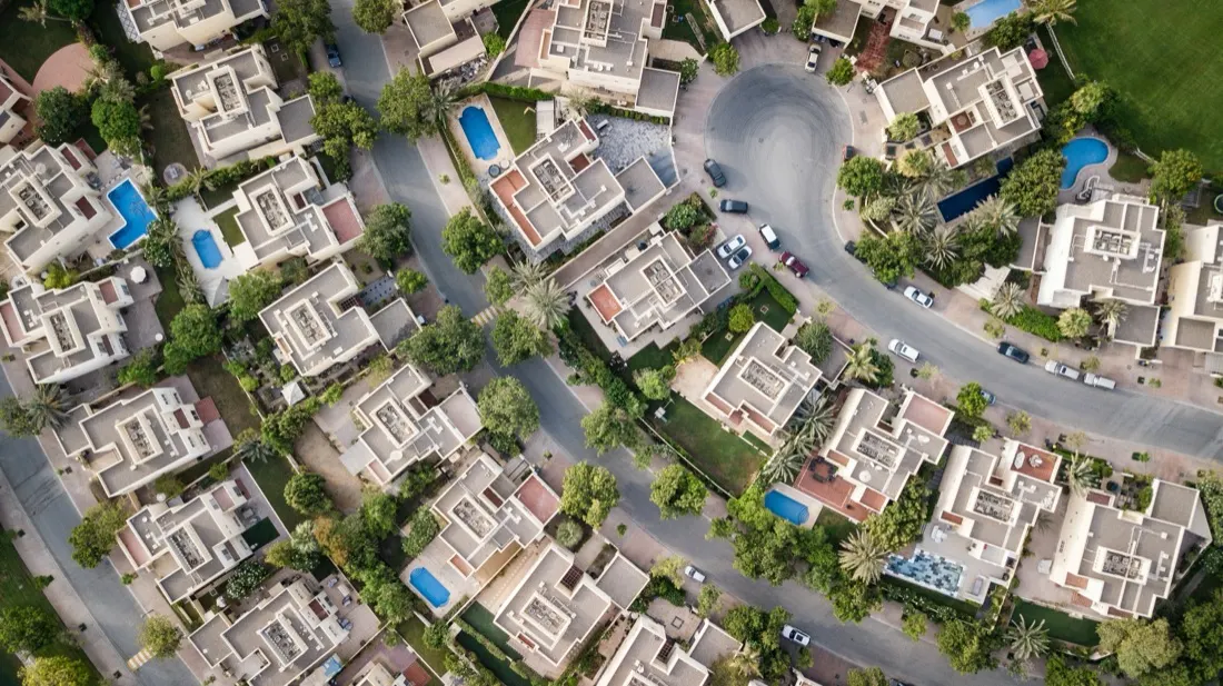 Aerial view of a suburban housing estate with pools and gardens, illustrating the hot 2021 housing market