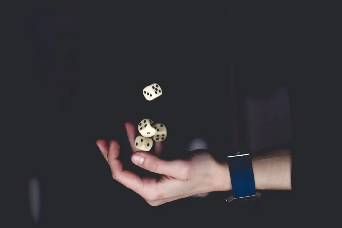 A hand tossing dice in darkness, symbolising the gamble of poor risk management