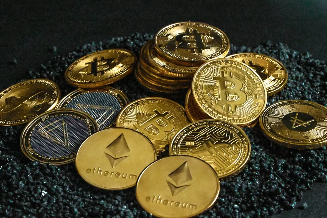 A close-up pile of gold and silver cryptocurrency coins, illustrating losses from crypto scams