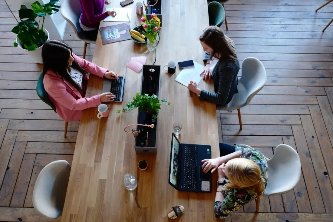 Three colleagues working at laptops around a shared table, illustrating the rise of contingent workers