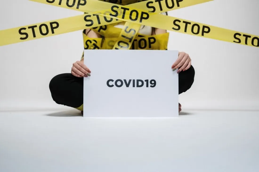 Woman behind yellow stop tape holding a sign reading Covid19, illustrating digital transformation becoming digital revolution
